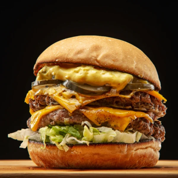 Close up of a big chicken smash burger with lettuce tomato and cheese on a black background - Seohara Kitchen