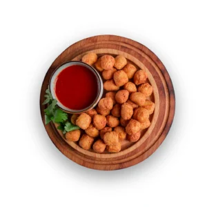 Golden fried chicken popcorn falling into a black bowl. Delicious frozen chicken snacks for kids delivery in Seohara.